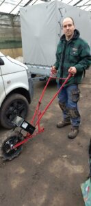 Person in warmer, dreckiger Arbeitskleidung präsentiert eine rote Radhacke